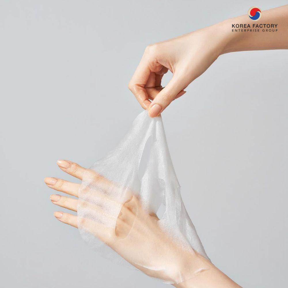 มือผู้หญิงกำลังดึงแผ่นมาส์กมือสีขาวออกจากหลังมือ พื้นหลังสีเทาอ่อน ด้านขวาเป็นกรอบข้อความ HAND PACK อธิบายบริการโรงงานรับผลิตแฮนด์แพ็ค CosKorea Group