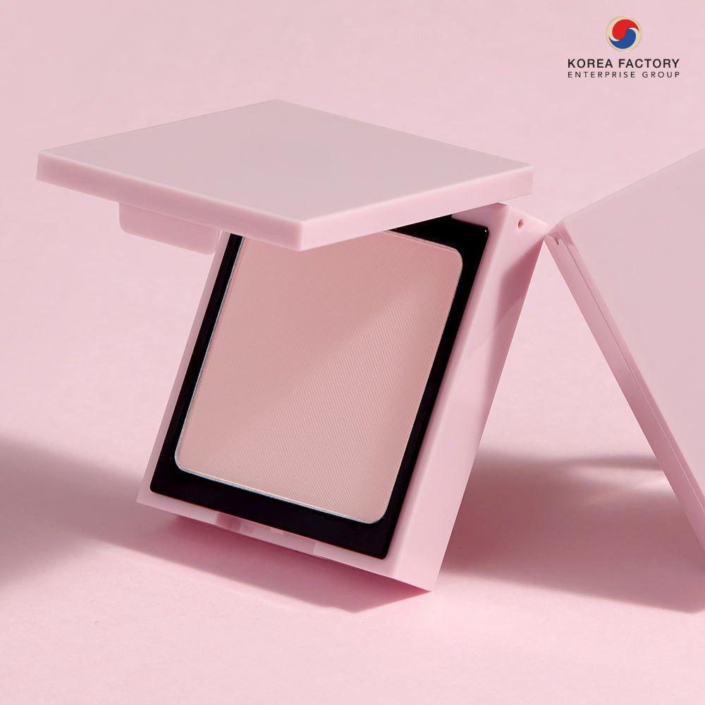 ตลับแป้งพัฟทรงสี่เหลี่ยมสีชมพูเปิดฝา โชว์พัฟและเนื้อแป้งบนพื้นหลังสีชมพู พร้อมโลโก้ Korea Factory Enterprise Group